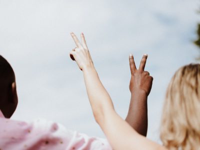 woman in white and pink floral shirt raising her hands